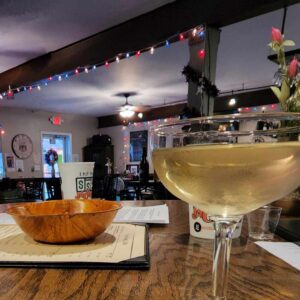 A glass of crisp white wine on a table inside the cozy ambiance of the Wine Café in Wilmington, IL